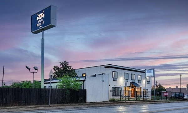 Hotel Dilley Grand exterior at dusk with roadside sign