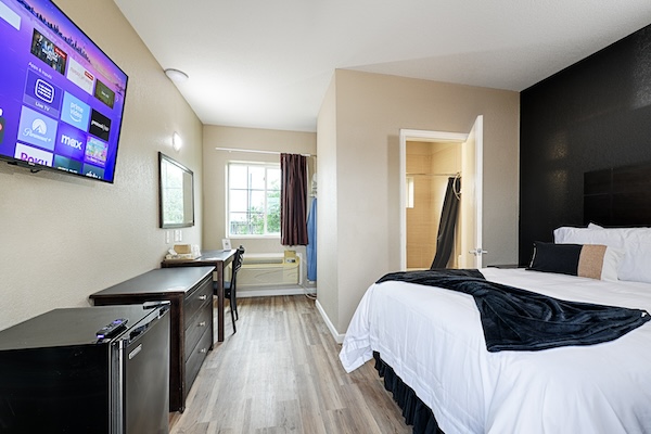 A furnished room with a queen bed at Hotel Dilley Grand
